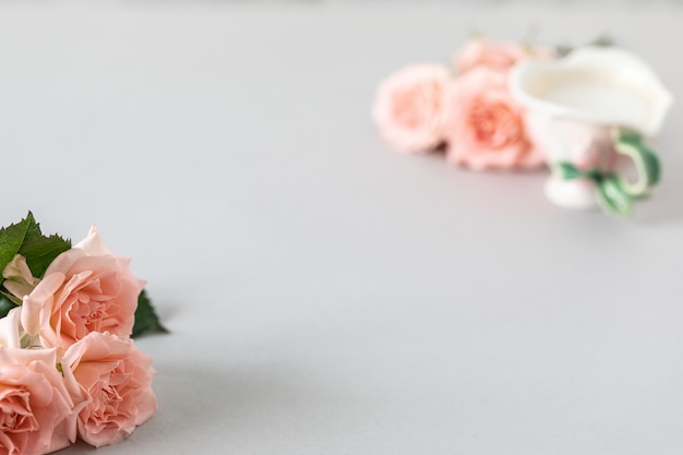 Taza de café, rosas rosadas, rosas rosadas sobre un gris