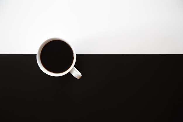Taza de café sobre un fondo blanco y negro plano