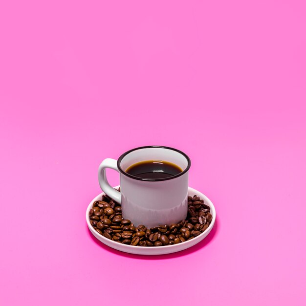 Taza de café sobre fondo rosa