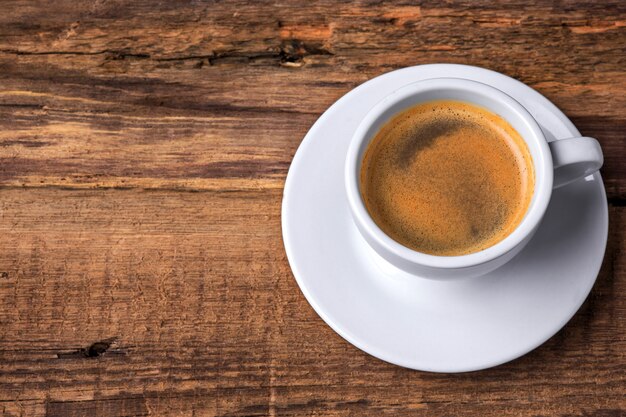 Taza de café sobre una mesa de madera. Fondo oscuro