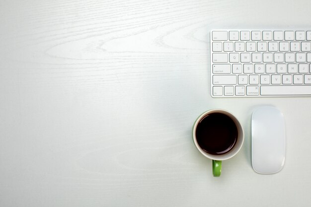 Una taza de café y teclado y mouse inalámbricos