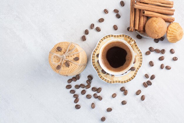 Taza de café con varias galletas y granos de café.