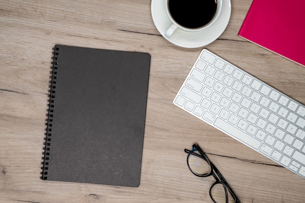 Taza de café, vasos, cuaderno negro y teclado