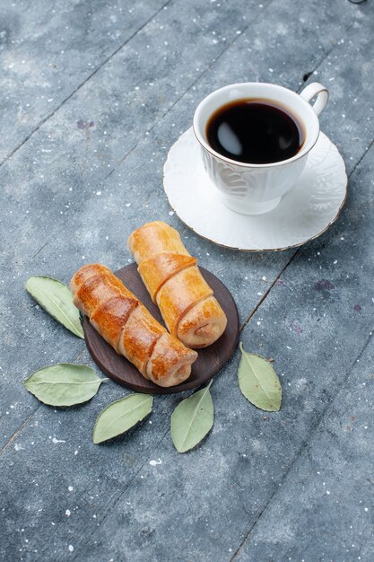 Taza de café vista lejana superior junto con brazaletes deliciosos dulces en gris