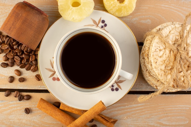 Una taza de café de la vista superior caliente y fuerte con semillas de café marrón frescas canela y galletas en el escritorio rústico crema bebida de semillas de café grano de la foto
