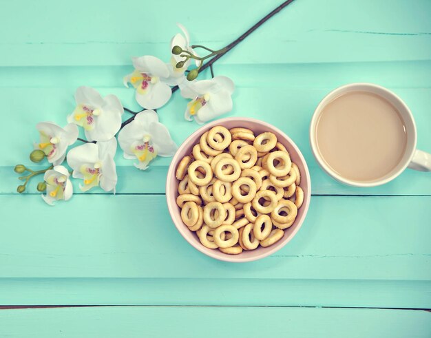 Taza de café en la vista superior de la mesa de madera vieja con flores frescas de primavera con gran plato de bubliks rusos