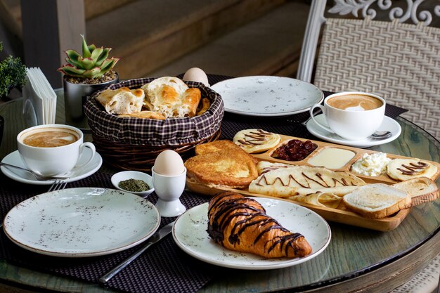 Taza de capuchino caliente y croissant de chocolate con desayuno