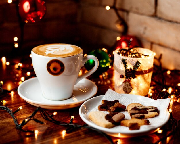 Taza de capuchino caliente y un plato con galletas