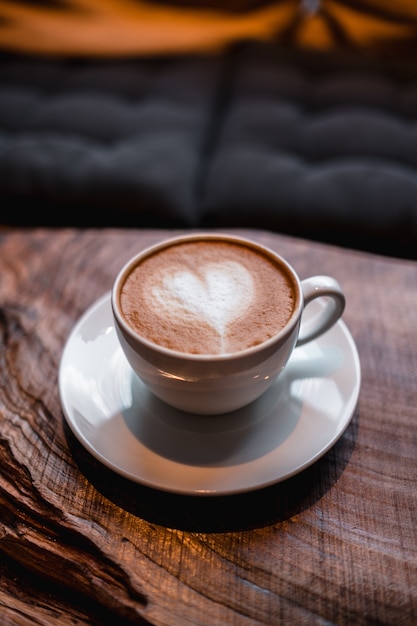 Taza de capuchino con un corazón sobre la mesa