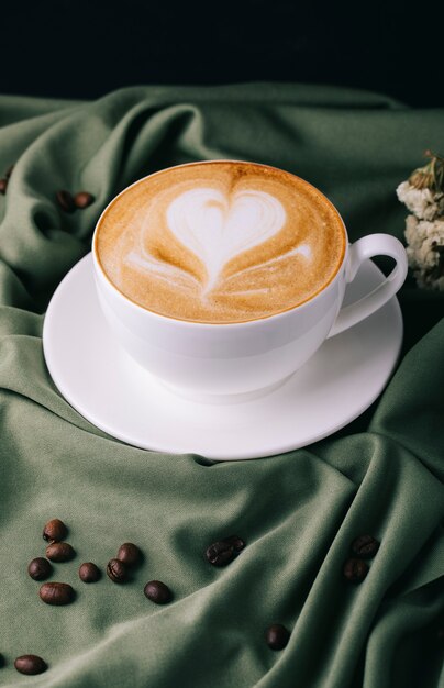 Taza de capuchino con granos de café sobre la mesa