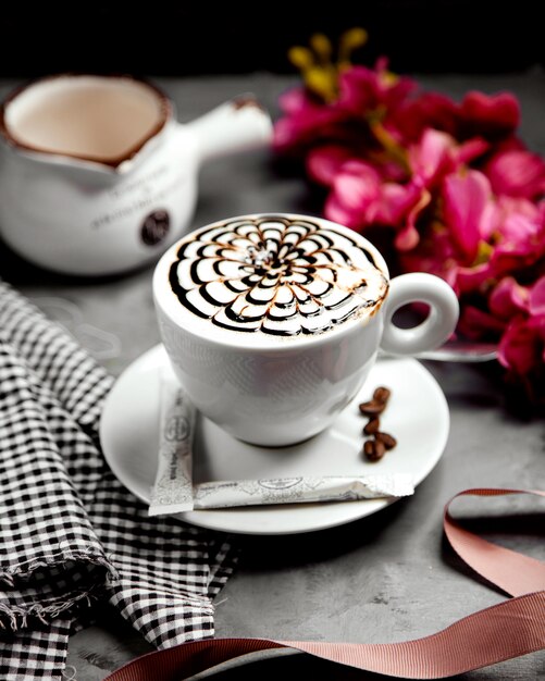 Una taza de capuchino con jarabe de chocolate flor latte-art