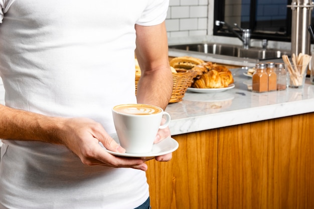 Taza de capuchino en mano de joven