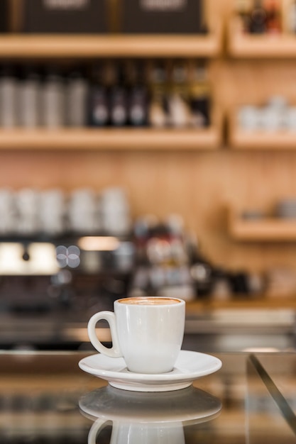 Foto gratuita taza de capuchino en el mostrador de vidrio