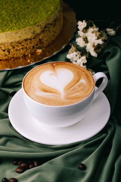 Taza de capuchino y pastel sobre la mesa