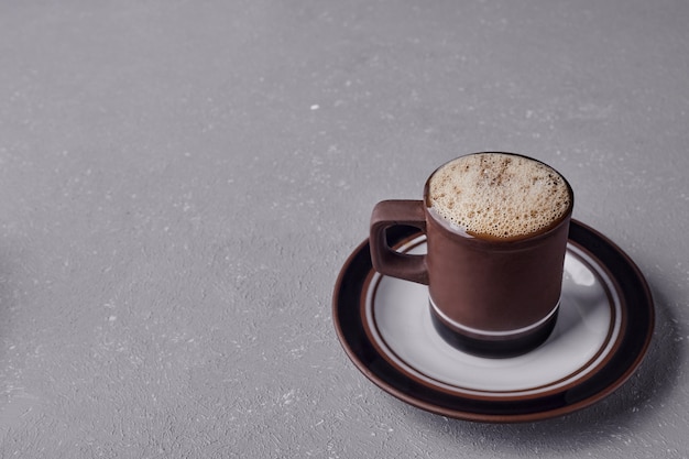 Una taza de capuchino sobre fondo gris.