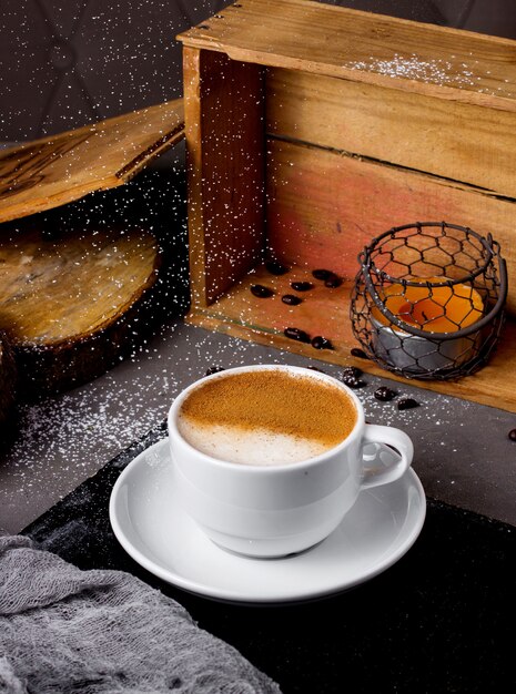 Taza de capuchino y vela en la caja de madera sobre la mesa