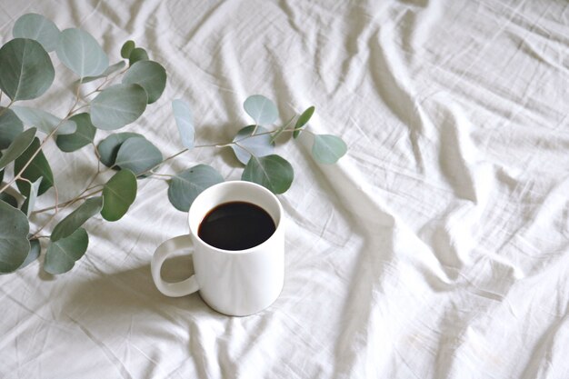 Taza de cerámica con café y hojas de chicle de plata