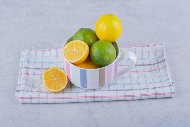 Taza de cerámica de jugosos limones frescos en piedra.