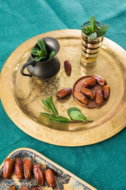 Foto gratuita taza cerca de la jarra con planta y frutos secos en bandeja