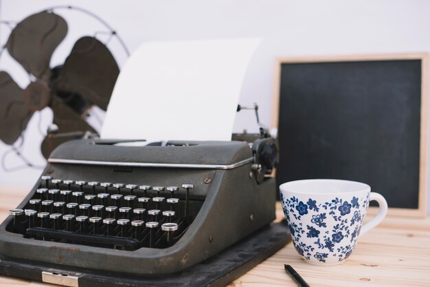 Taza cerca de la máquina de escribir retro