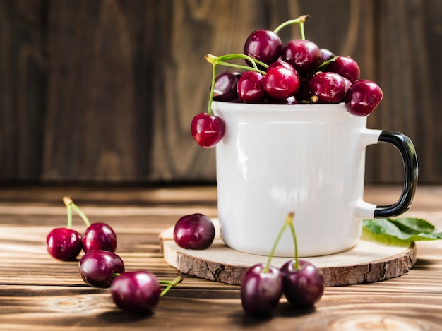 Taza de cereza dulce fresca sobre fondo de madera