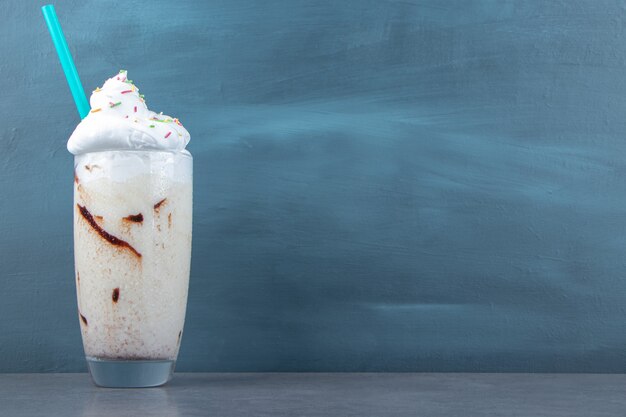 Una taza de cristal de batido dulce con crema batida y chispas. Foto de alta calidad