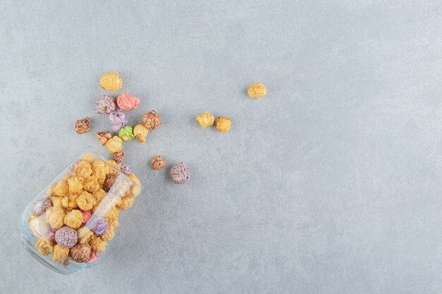 Una taza de cristal llena de dulces palomitas de maíz multicolores.