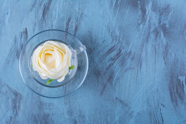 Taza de cristal de rosa blanca colocada en azul.