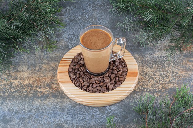 Una taza de delicioso café con granos de café sobre tabla de madera. Foto de alta calidad