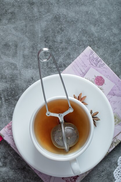 Una taza de delicioso té con anís estrellado en un plato blanco.