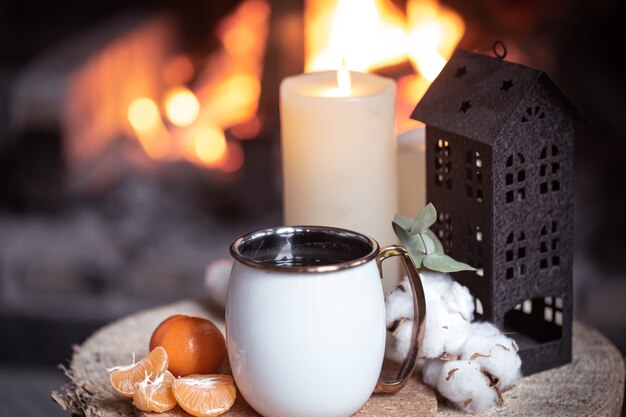 Una taza con elementos decorativos en un tocón de madera cerca de la chimenea. El concepto de unas vacaciones en un pueblo fuera de la ciudad.