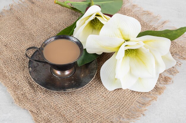 Taza de espresso y flores blancas sobre arpillera