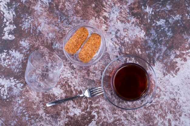 Una taza de espresso con galletas de sésamo en un platillo de vidrio en el mármol, vista superior
