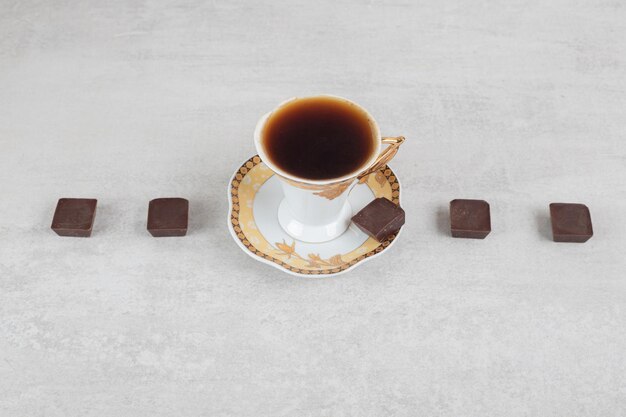 Taza de espresso con trozos de chocolate sobre la superficie de mármol