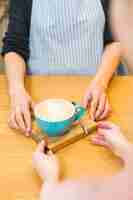 Foto gratuita taza femenina de la porción del barista de café con leche en la tajadera de madera