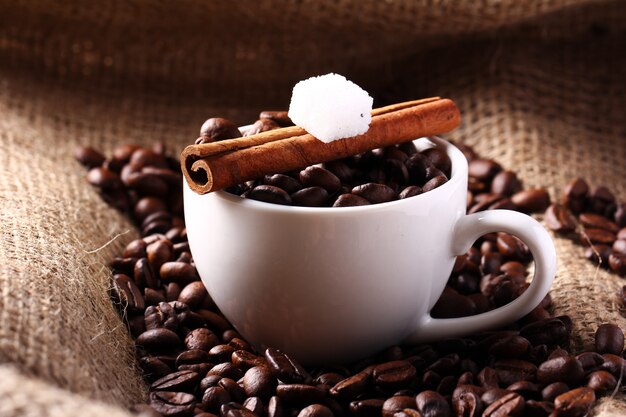 Taza con granos de café y canela en rama