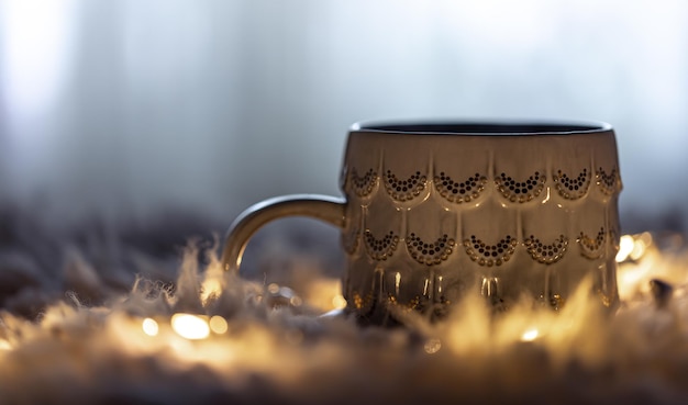 Taza hermosa sobre un fondo borroso en la oscuridad con guirnaldas