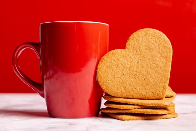 Taza junto a galletas de corazón