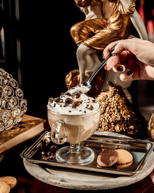 taza de latte con crema adornada con trozos de chocolate y café