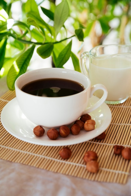 Taza de leche y café sobre estera de bambú.