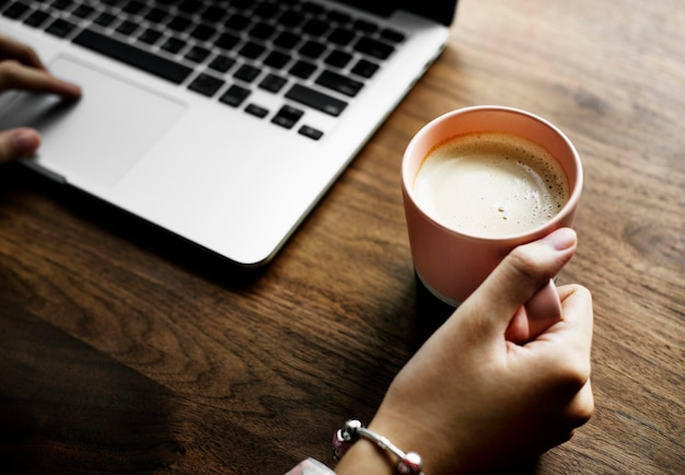 Una taza de leche caliente agradable al lado de una computadora portátil