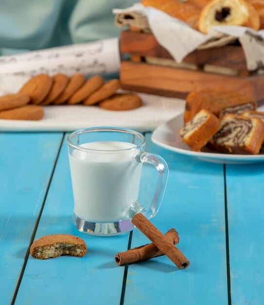 Una taza de leche con canela y una galleta.