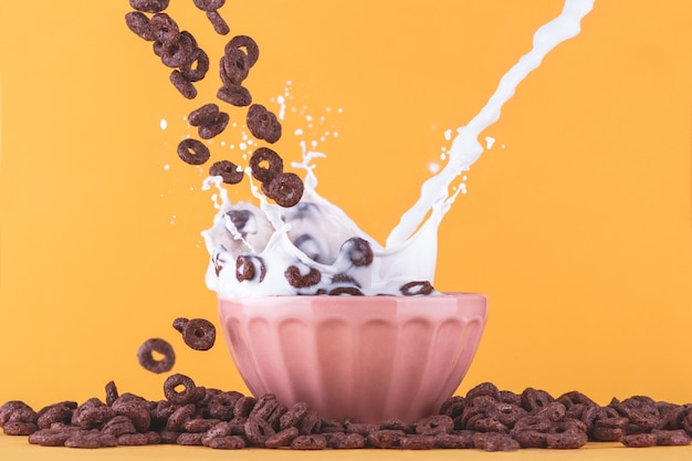 Foto gratuita taza de leche con cereales de chocolate cayendo y salpicaduras de leche.