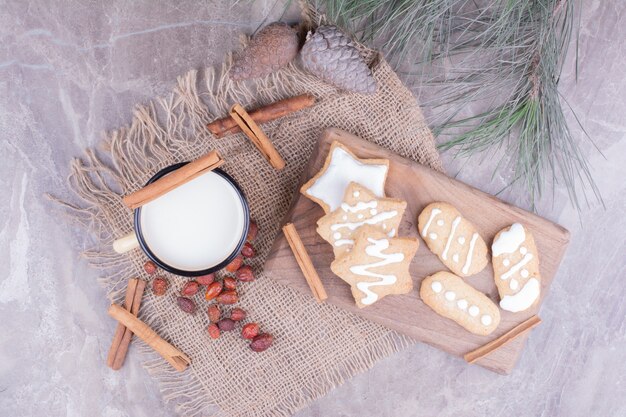 Una taza de leche con pan de jengibre estrella y canela alrededor