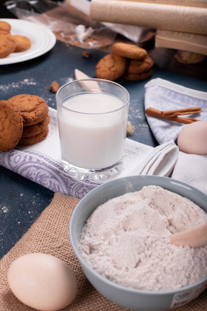 Taza de leche con tarro de galletas y harina