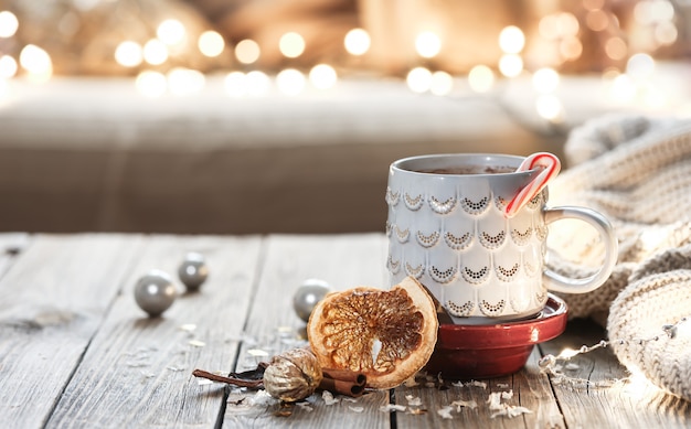 Taza de Navidad con bebida caliente sobre fondo borroso con bokeh.