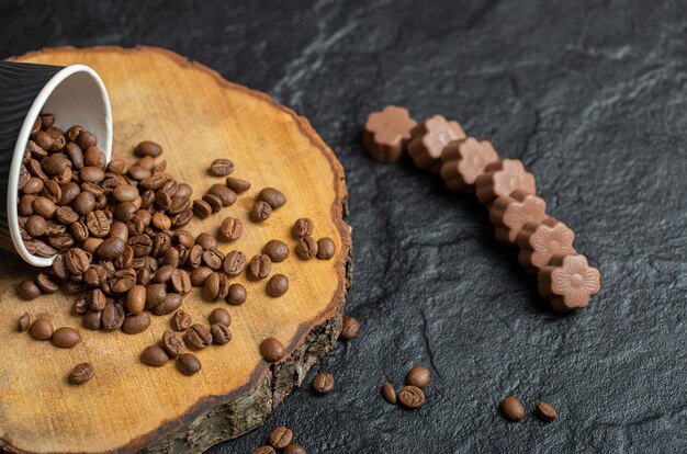 Una taza negra llena de granos de café sobre tabla de madera.