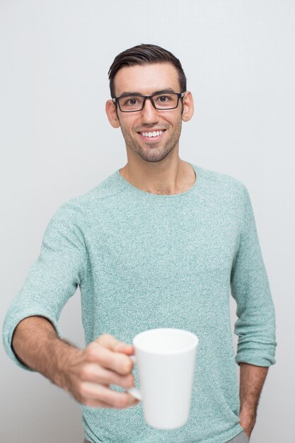 Taza de ofrecimiento del hombre sonriente joven hermoso de té