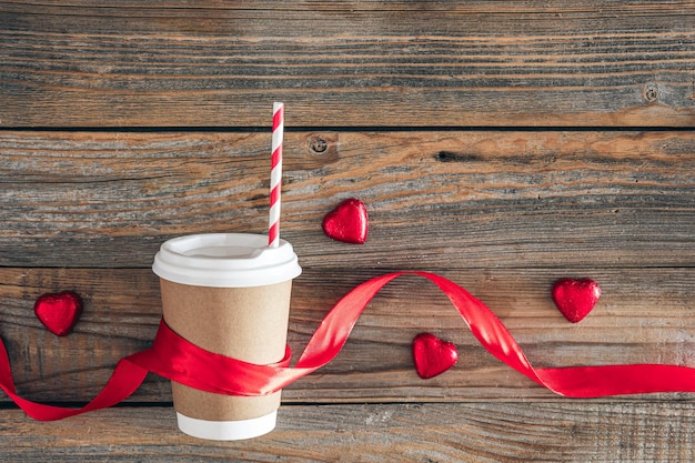 Foto gratuita taza de papel y caramelos en forma de corazón en un fondo de madera vista superior