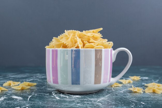 Foto gratuita taza de pasta farfalle sobre fondo azul. foto de alta calidad